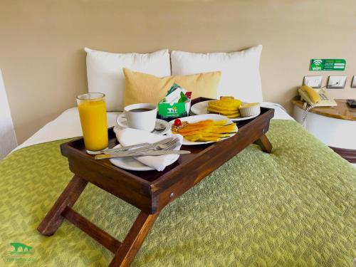 a tray of breakfast food on a bed with a glass of orange juice at Hotel Puente Nacional & Spa in Puente Nacional