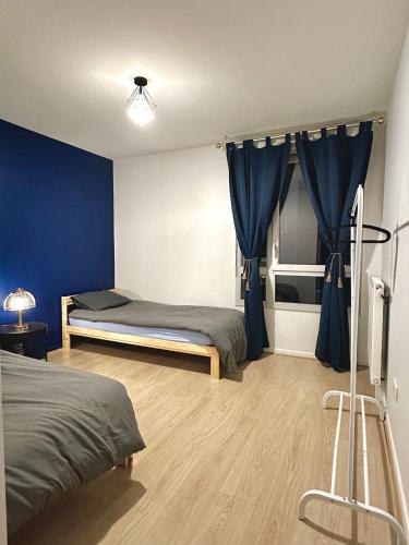 ein Schlafzimmer mit zwei Betten und einer blauen Wand in der Unterkunft Proche stade de France avec parking in Saint-Denis