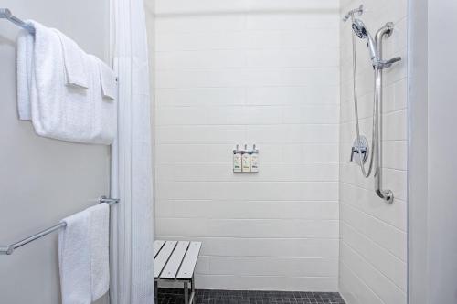 a white bathroom with a shower and a bench at Holiday Inn Express & Suites - Miramar by IHG in Miramar