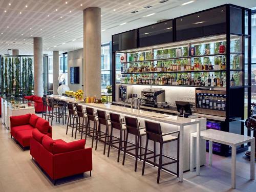 a bar in a restaurant with red bar stools at Pullman Paris Roissy Cdg Airport in Roissy-en-France