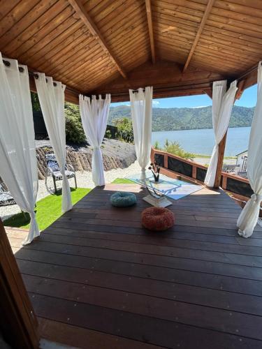 a wooden deck with white curtains and a view of the ocean at The Petite Suite in Havelock