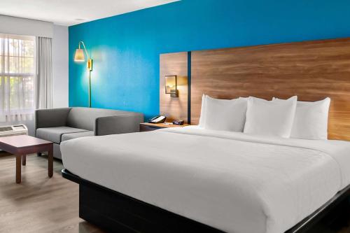 a hotel room with a large bed and a chair at Clarion Inn Falls Church-Arlington in Falls Church