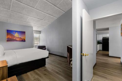 a hotel room with a bed and a hallway at Clarion Inn Falls Church-Arlington in Falls Church