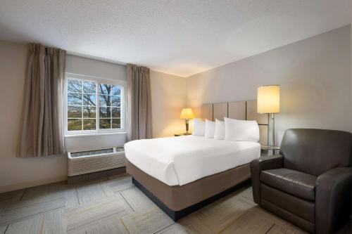 a bedroom with a bed and a chair and a window at Sonesta Simply Suites Huntsville Research Park in Huntsville