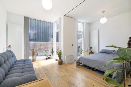 a bedroom with a bed and a couch and windows at Spitalfields Market Garden Flat in London