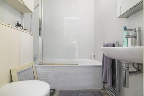 a bathroom with a tub and a sink and a toilet at Spitalfields Market Garden Flat in London
