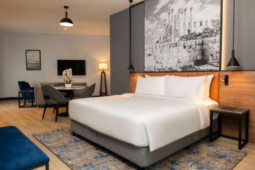 a bedroom with a large white bed and a dining room at Radisson Blu Hotel, Amman Galleria Mall in Amman