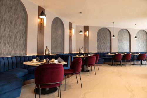 a dining room with tables and red chairs and tablesktop at Radisson Blu Hotel, Amman Galleria Mall in Amman
