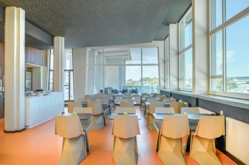 a large room with chairs and tables and windows at Prize by Radisson, Dortmund City in Dortmund