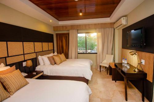 a hotel room with two beds and a television at Hotel Faranda Guayacanes, a member of Radisson Individuals in Chitré