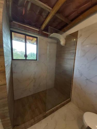 a bathroom with a glass shower with a window at Casa Campestre Mi Refugio in Pedro Vicente Maldonado