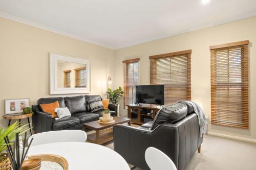 sala de estar con muebles de cuero y TV de pantalla plana en Marcotta Guest Suite - Moments to Golf Course, en Orange