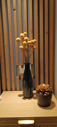 a black vase on a table with a bowl of flowers at Filoxenia Luxury Apartment in Nafplio
