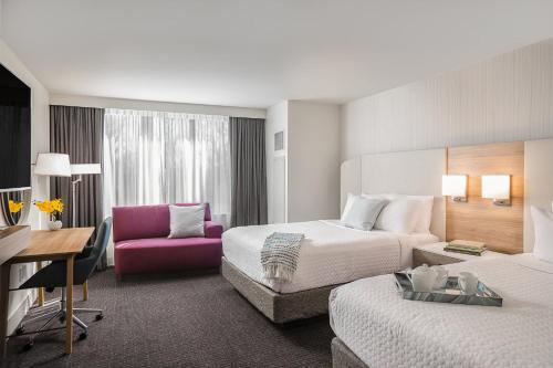 a hotel room with two beds and a pink chair at Crowne Plaza Atlanta Perimeter at Ravinia by IHG in Atlanta