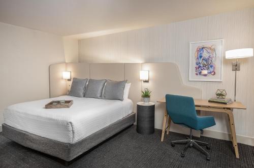 a bedroom with a bed and a desk with a blue chair at Crowne Plaza Atlanta Perimeter at Ravinia by IHG in Atlanta