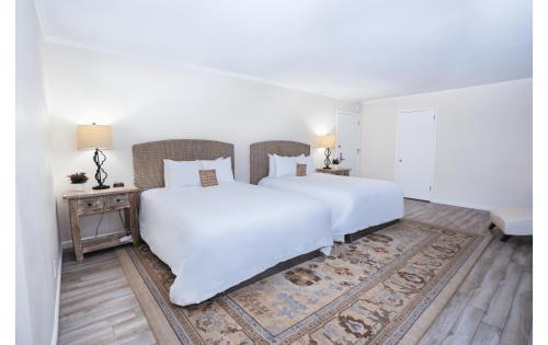 a white bedroom with a large white bed and a table at Pacific Crest Hotel Santa Barbara in Santa Barbara
