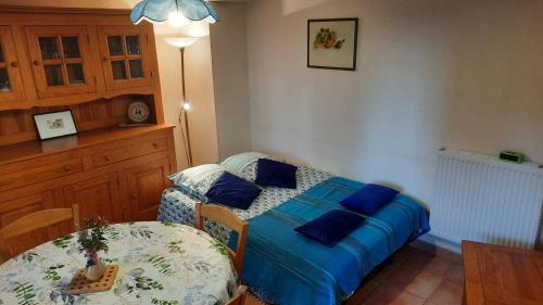 a bedroom with a bed with blue pillows and a table at La petite maison dans la prairie in Cassaignes