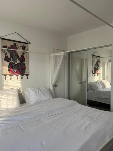 a bedroom with a large white bed and a mirror at Laurel house weho historic district in Los Angeles