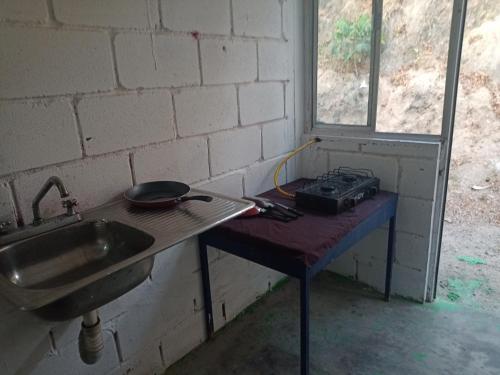 uma mesa num quarto com um lavatório e um fogão em Casa Adelita em Barra de la Cruz