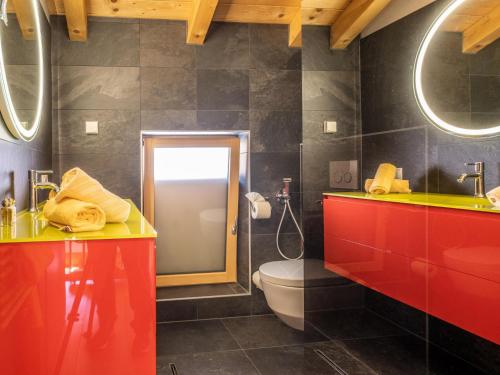 a bathroom with red and green cabinets and a toilet at Nature Lodge Kaprun B in Kaprun