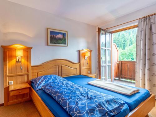 a bedroom with a blue bed and a window at Pension Blaiken XL in Scheffau am Wilden Kaiser