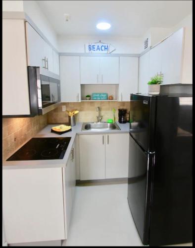 uma cozinha com um frigorífico preto e um lavatório em 1 Stylish SoBe Condo 1/2 Block From The Beach!!! em Miami Beach