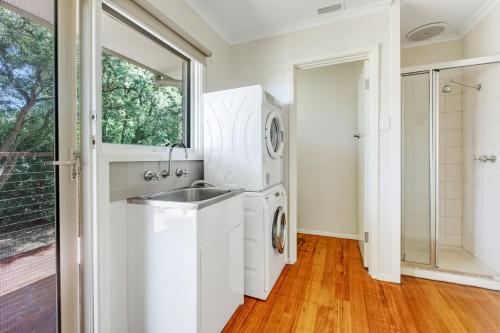 uma cozinha com um lavatório e uma máquina de lavar roupa em Sunlit Suburbia - A Breezy Abode in Glen Waverley em Glen Waverley
