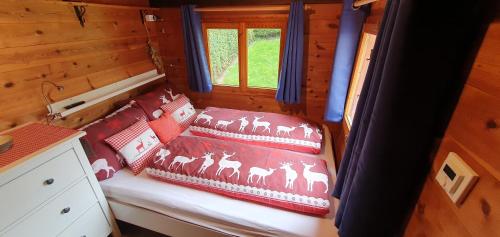 ein Bett in einer Holzhütte mit Kissen darauf in der Unterkunft Kleine Blockhütte im Garten 