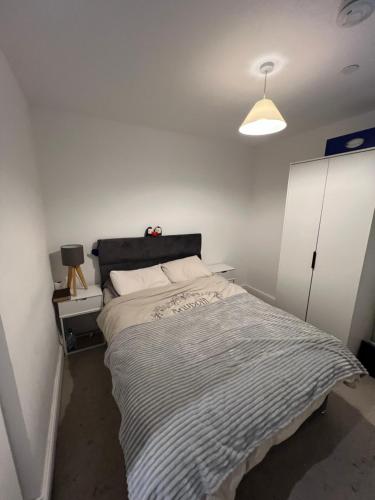 a bedroom with a large bed and a white wall at Stunning Modern Apartment in High Wycombe