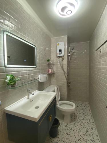 ein Bad mit einem Waschbecken und einem WC sowie einen TV in der Unterkunft PTJ Style Condotel คอนโดเมืองทอง P1 in Ban Song Hong