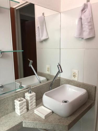 a bathroom with a white sink and a mirror at Apartamento mobiliado in Vespasiano