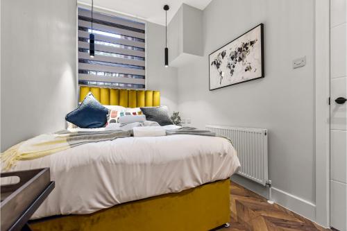 a bedroom with a large bed with a yellow headboard at Lovely 2 BR with Grill in London