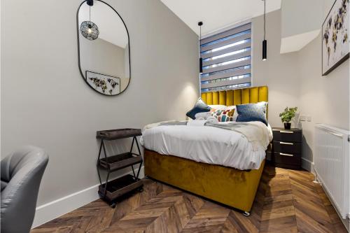 a bedroom with a yellow bed with a mirror at Lovely 2 BR with Grill in London