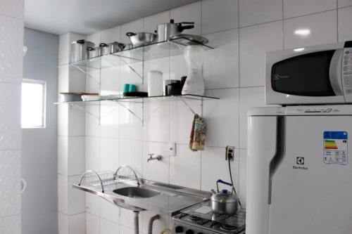 una cocina con fregadero y microondas en CASA INDIVIDUAL CoM PISCINA, AR, WI-FI, ATÉ 16 PESSOAS, en Itapema