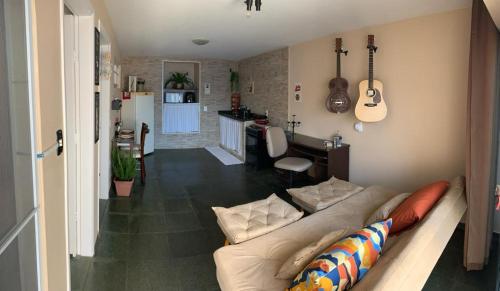 a living room with a couch and a kitchen with a guitar at Studio do Wander in Amparo