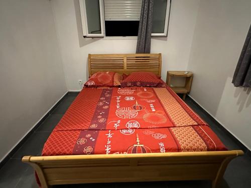 a bed with a red quilt on it in a room at La caraïbe dans la station balnéaire 3 in Saint-François