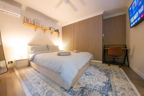 a bedroom with a white bed and a tv at Peaceful Studio Close to shops, motorway, national forest & koalas! in Tanah Merah