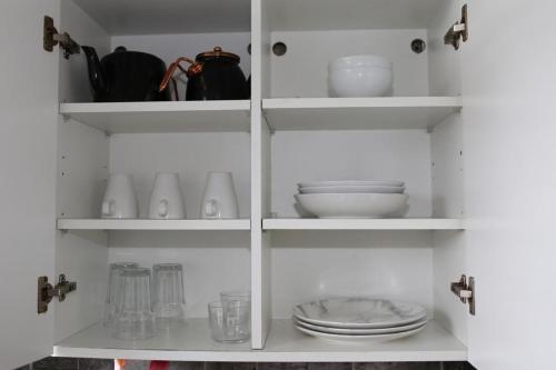 a white cupboard with plates and dishes in it at 2 bedroom apartment with balcony near Tottenham Hostpur Stadium in Edmonton