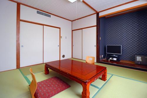 a living room with a wooden table and a tv at Shugyoku no Yu Yakushido Onsen in Oshu