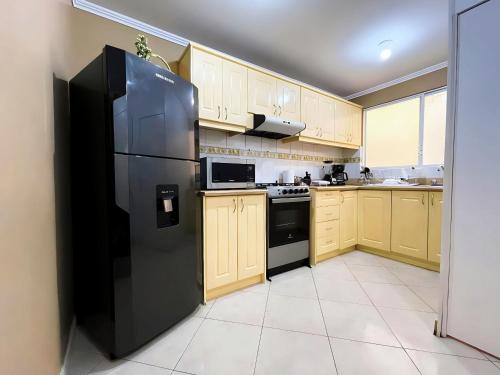 eine Küche mit einem schwarzen Kühlschrank und Holzschränken in der Unterkunft Apartamento en la mejor ubicación, centro de Loja in Loja