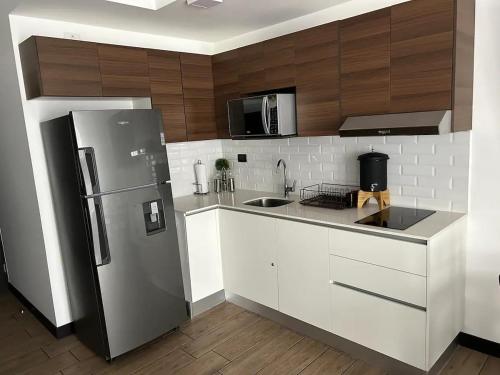 a kitchen with a stainless steel refrigerator and white cabinets at EÓN 11 - Moderno, vista volcán, aire acondicionado in Guatemala