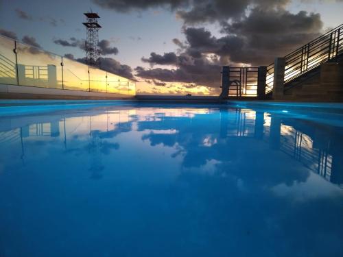 a swimming pool with a sunset in the background at Condo Kiaraluna in Playa del Carmen