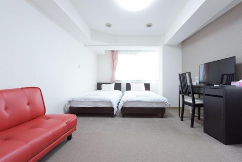 une chambre d'hôtel avec deux lits et un canapé rouge dans l'établissement Hirojo Building 203,303,403,603,703 - Vacation STAY 15454, à Tokyo
