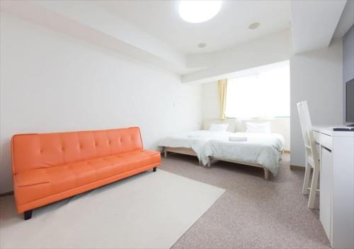 un sofá naranja en una habitación blanca con cama en Hirojo Building 203,303,403,603,703 - Vacation STAY 15419 en Tokio