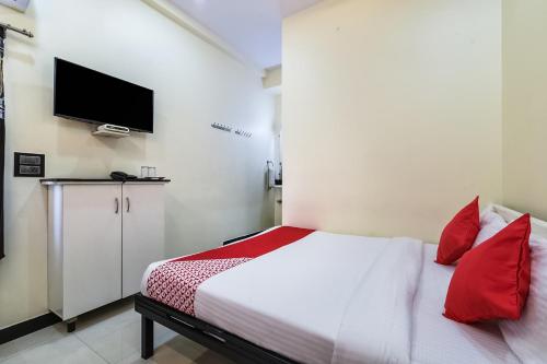 a bedroom with a bed with red pillows and a tv at Hotel Spar Grand in Visakhapatnam