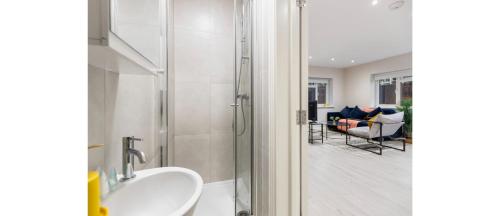 a bathroom with a sink and a shower and a living room at Tranquil Retreat in Hendon: Comfort & Style Await in The Hyde