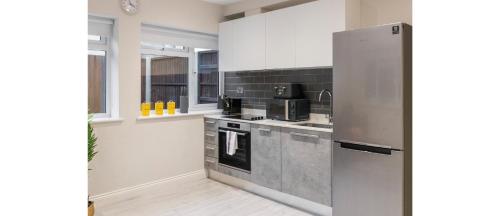 a kitchen with white cabinets and a stainless steel refrigerator at Tranquil Retreat in Hendon: Comfort & Style Await in The Hyde