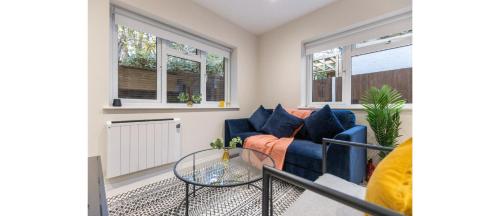 a living room with a couch and two windows at Tranquil Retreat in Hendon: Comfort & Style Await in The Hyde