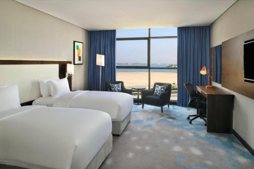 ジッダにあるHoliday Inn Jeddah Corniche, an IHG Hotelのベッド2台とデスクが備わるホテルルームです。