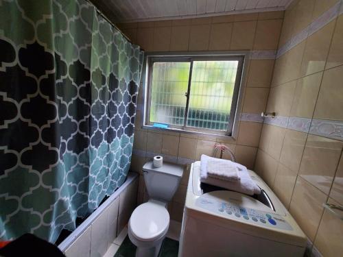 baño con aseo y lavabo y ventana en Acogedora Cabaña en la playa, en Valdivia